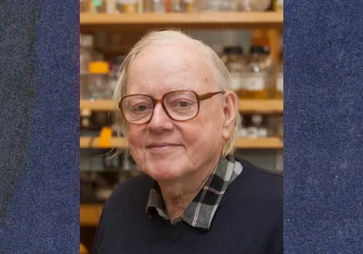 Howard Berg wearing glasses, looking at the camera with his lab in the background